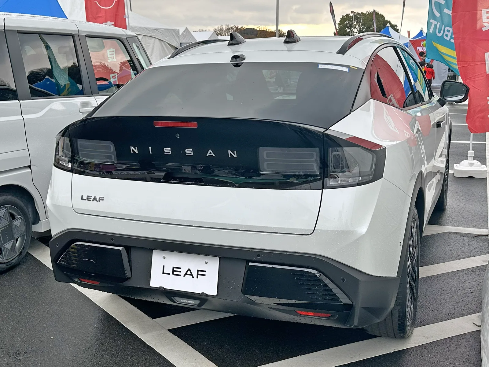 ลีฟเจนใหม่สีขาว มุมท้ายตรง เห็นไฟท้ายแถบยาวคาดตัวรถและป้าย LEAF ชัดเจน