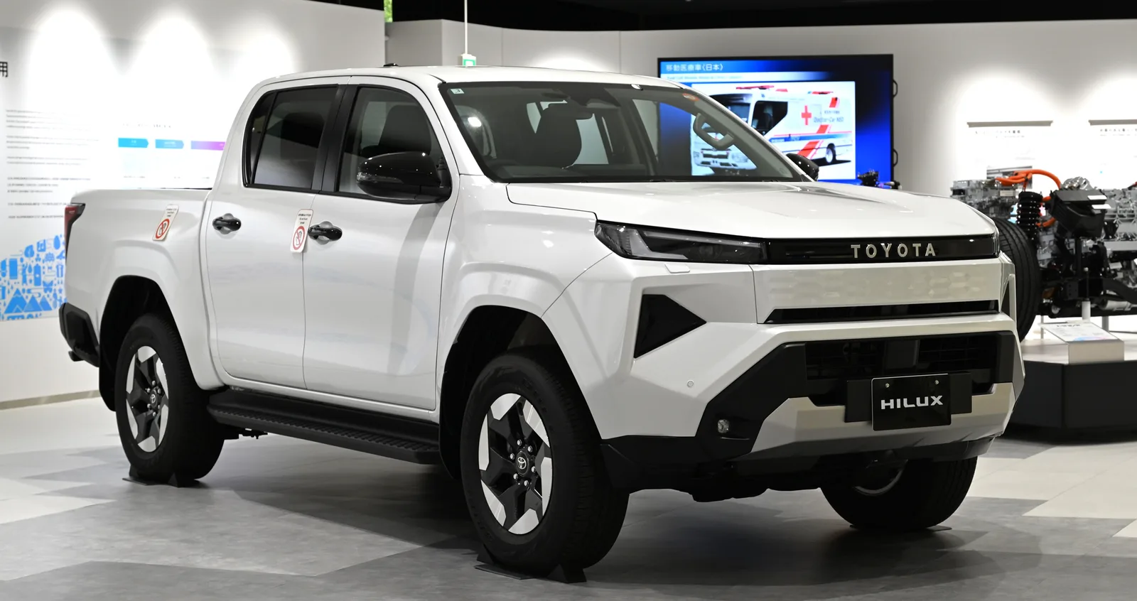 Hilux BEV สีขาว มุมท้ายสามส่วนในโชว์รูม โชว์กระบะท้ายและไฟท้ายทรงใหม่