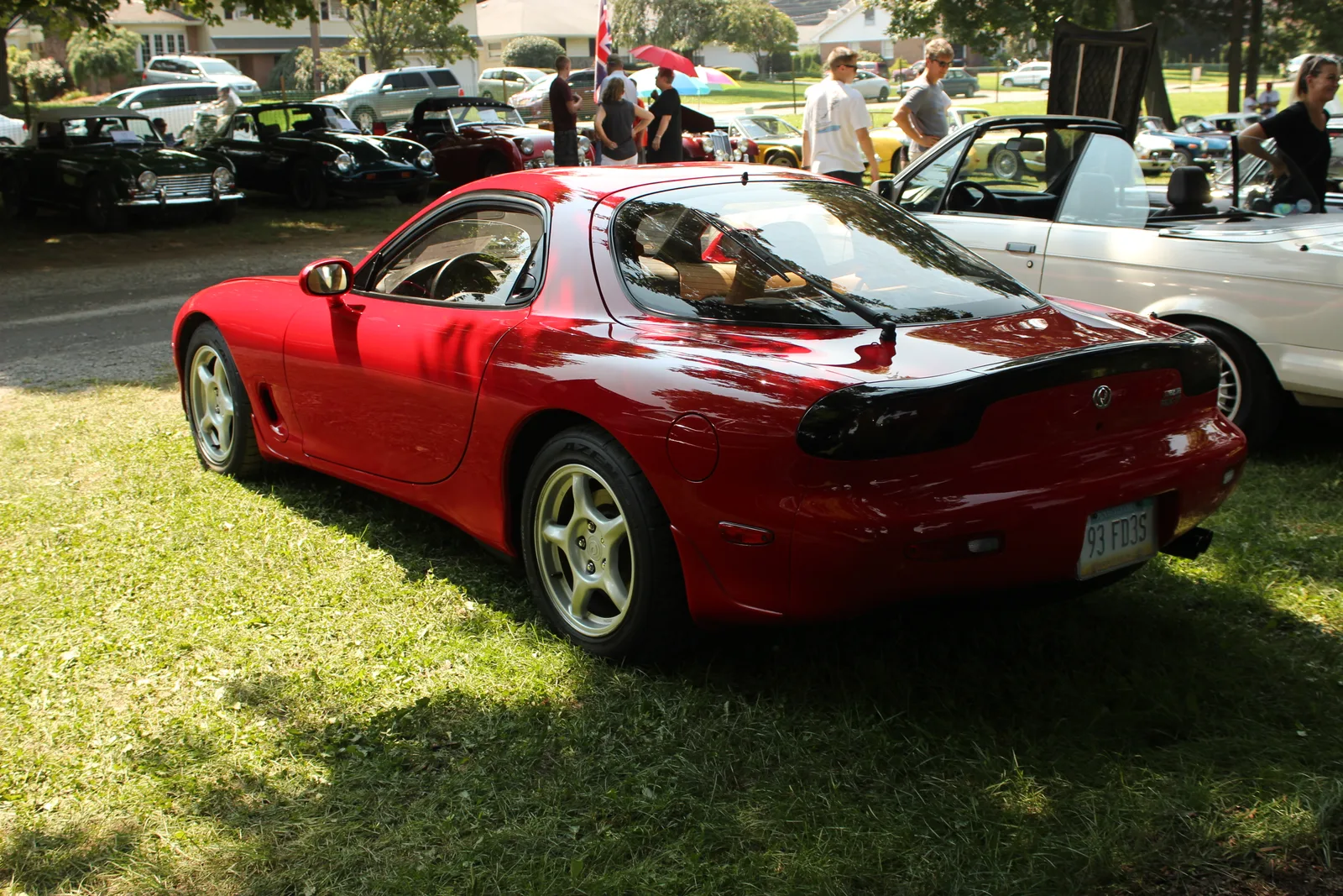 มาสด้า RX-7 (FD) สีแดงสด มุมท้ายสามส่วน จอดในงานรวมรถคลาสสิกกลางแจ้ง
