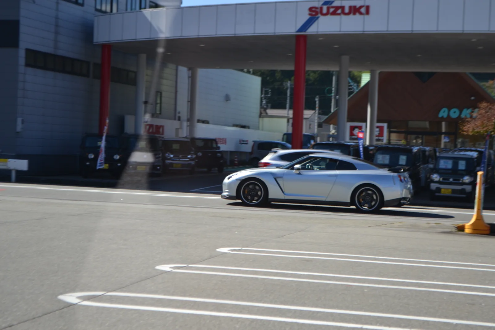 GT-R R35 สีเงิน มุมข้าง กำลังแล่นผ่านโชว์รูมรถในญี่ปุ่น