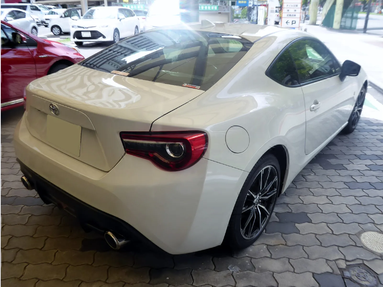 โตโยต้า 86 สีครีม มุมท้ายสามส่วน จอดหน้าโชว์รูมในญี่ปุ่น เห็นไฟท้ายทรงคมและท่อไอเสียคู่