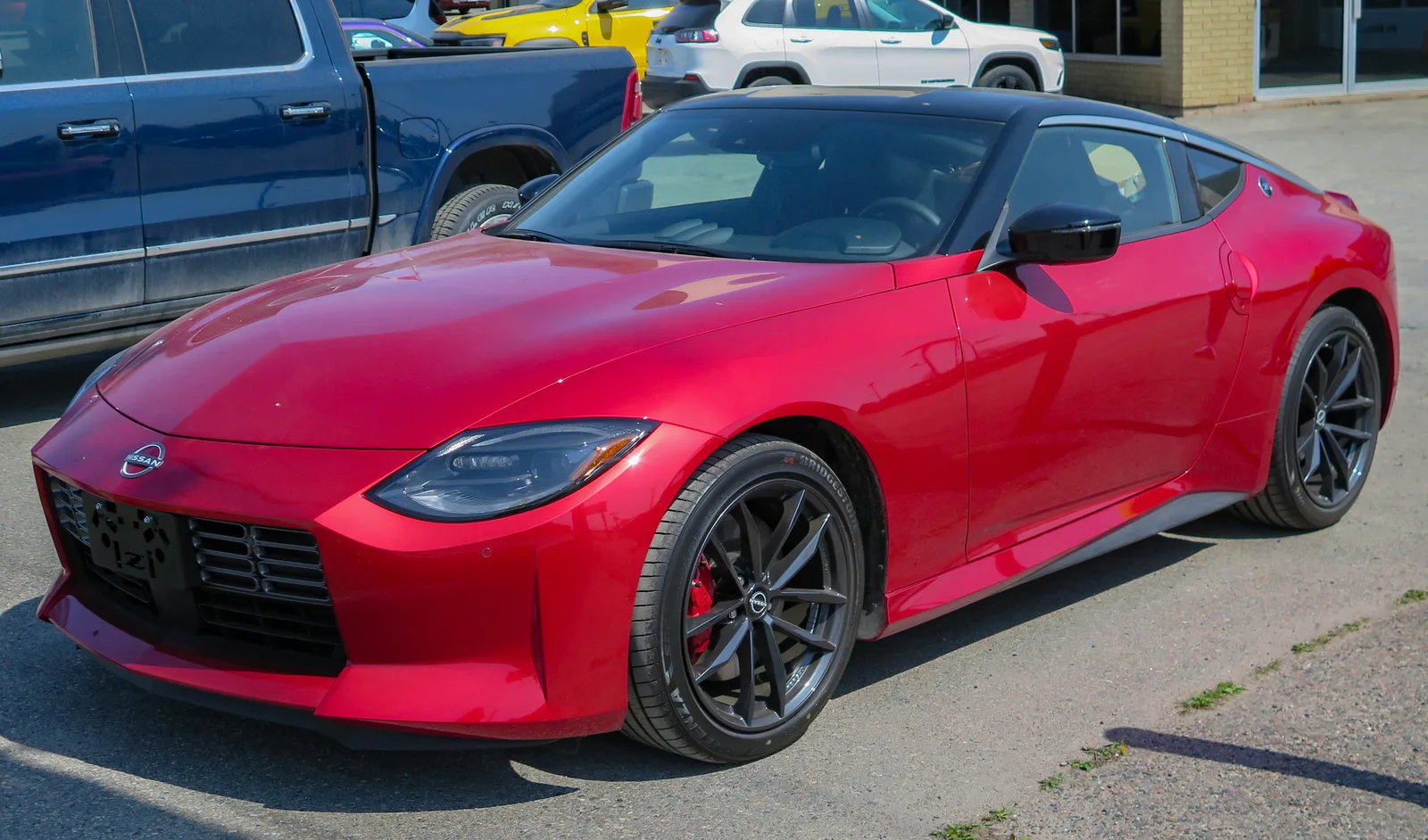 Nissan Z รุ่นมาตรฐานสีแดง มุมหน้าเฉียงในลานจอด โชว์เส้นตัวถังเจนเนอเรชั่นใหม่