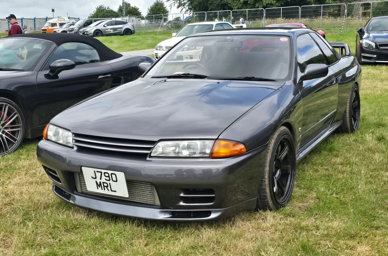 นิสสัน สกายไลน์ GT-R R32 สีเทาเข้ม มุมหน้าสามส่วน บนสนามหญ้างานโชว์รถ