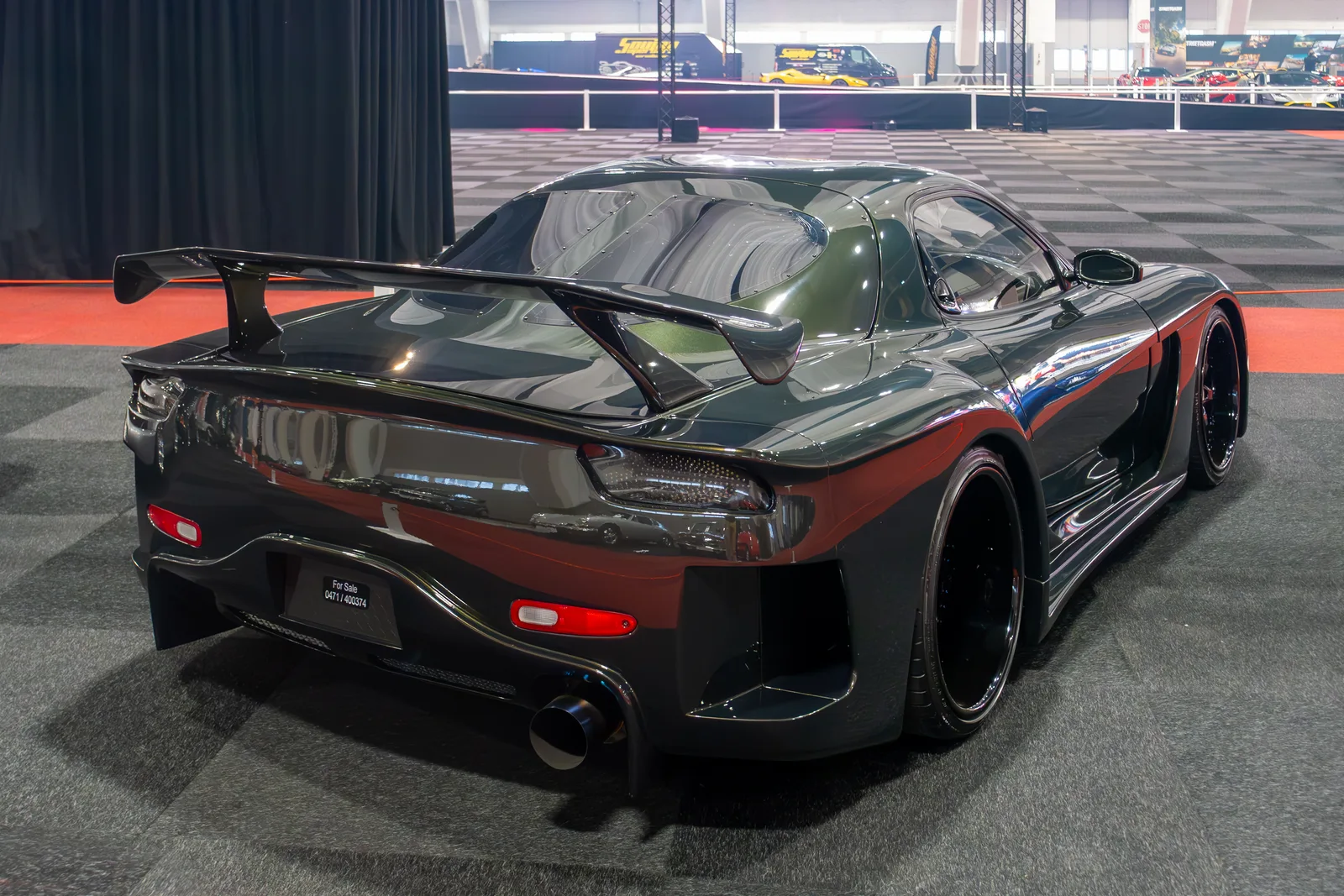 RX-7 FD ชุดแต่ง Veilside สีเขียวเข้ม มุมท้ายสามส่วน เห็นปีกใหญ่และท่อไอเสียกลางกันชน