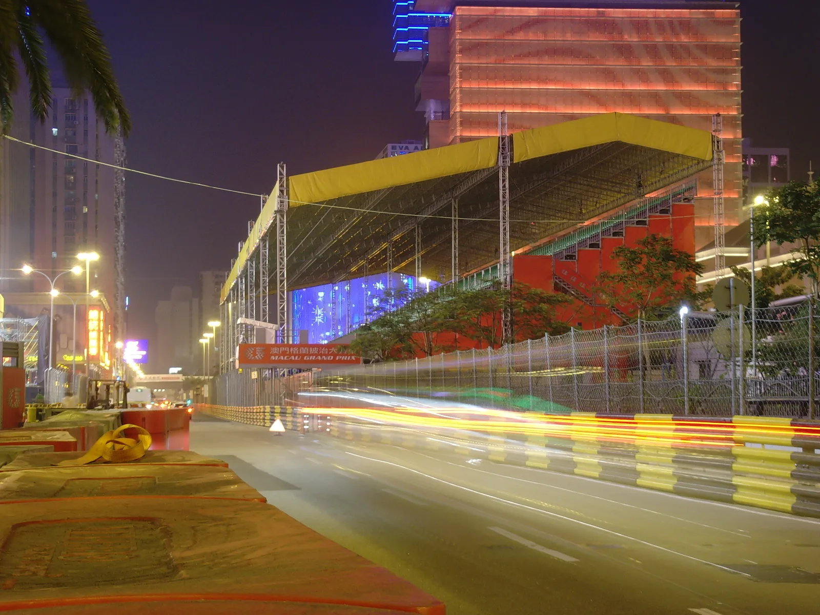 แสงไฟรถวิ่งยาวผ่านอัฒจันทร์ชั่วคราวยามค่ำคืนริมถนนสนาม Macau Grand Prix