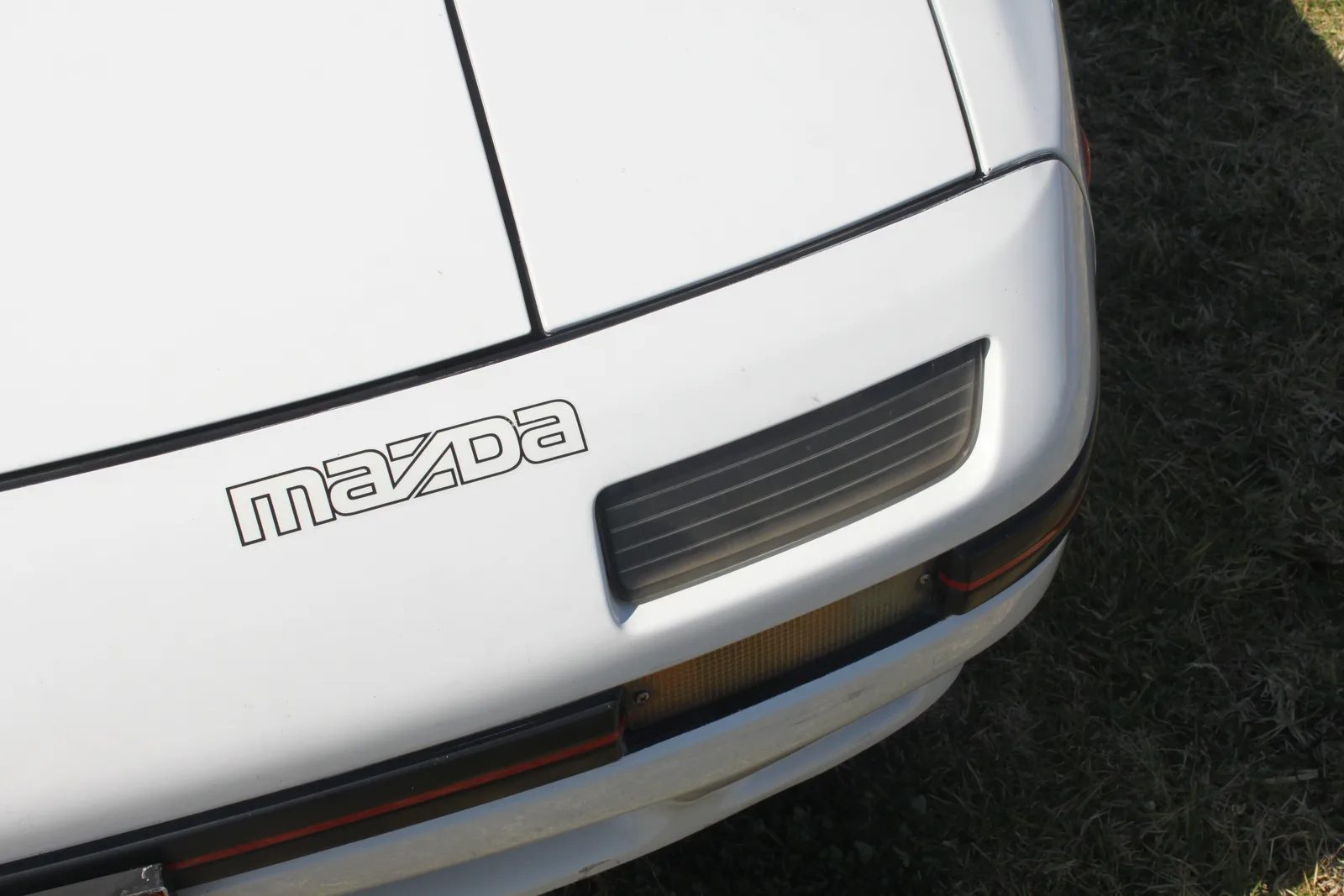 ดีเทลหน้ารถ RX-7 FC3S สีขาว ไฟหน้า ไฟเลี้ยว และโลโก้ Mazda แบบเดิม