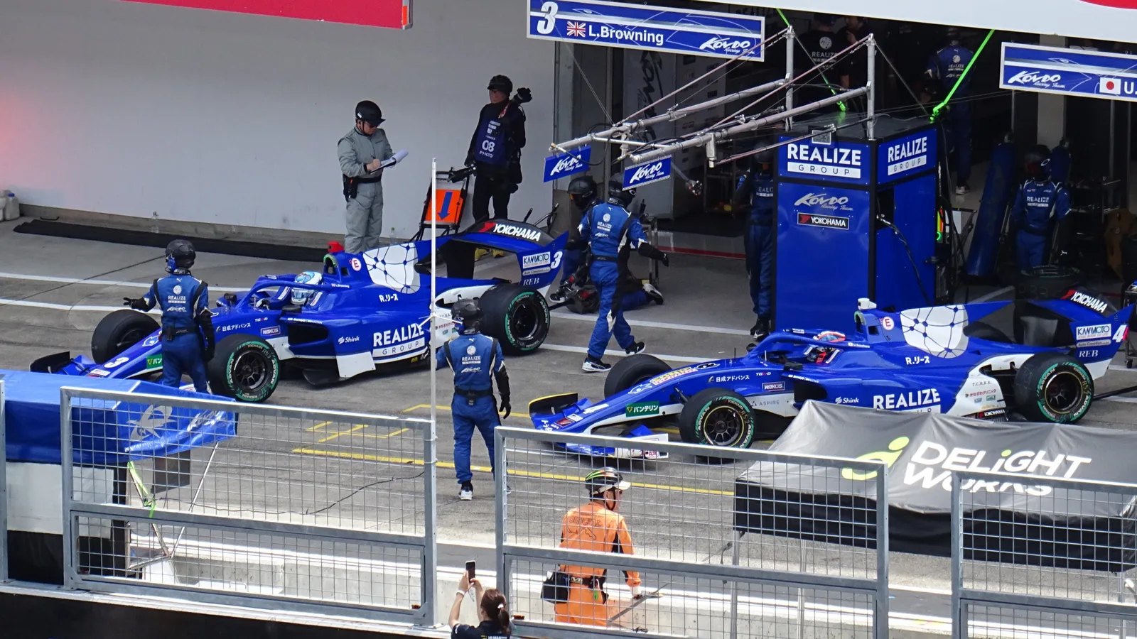 ทีม Realize Kondo Racing ในพิทซูซูกะ มองจากด้านบน เห็นรถสองคันและช่างกำลังทำงาน
