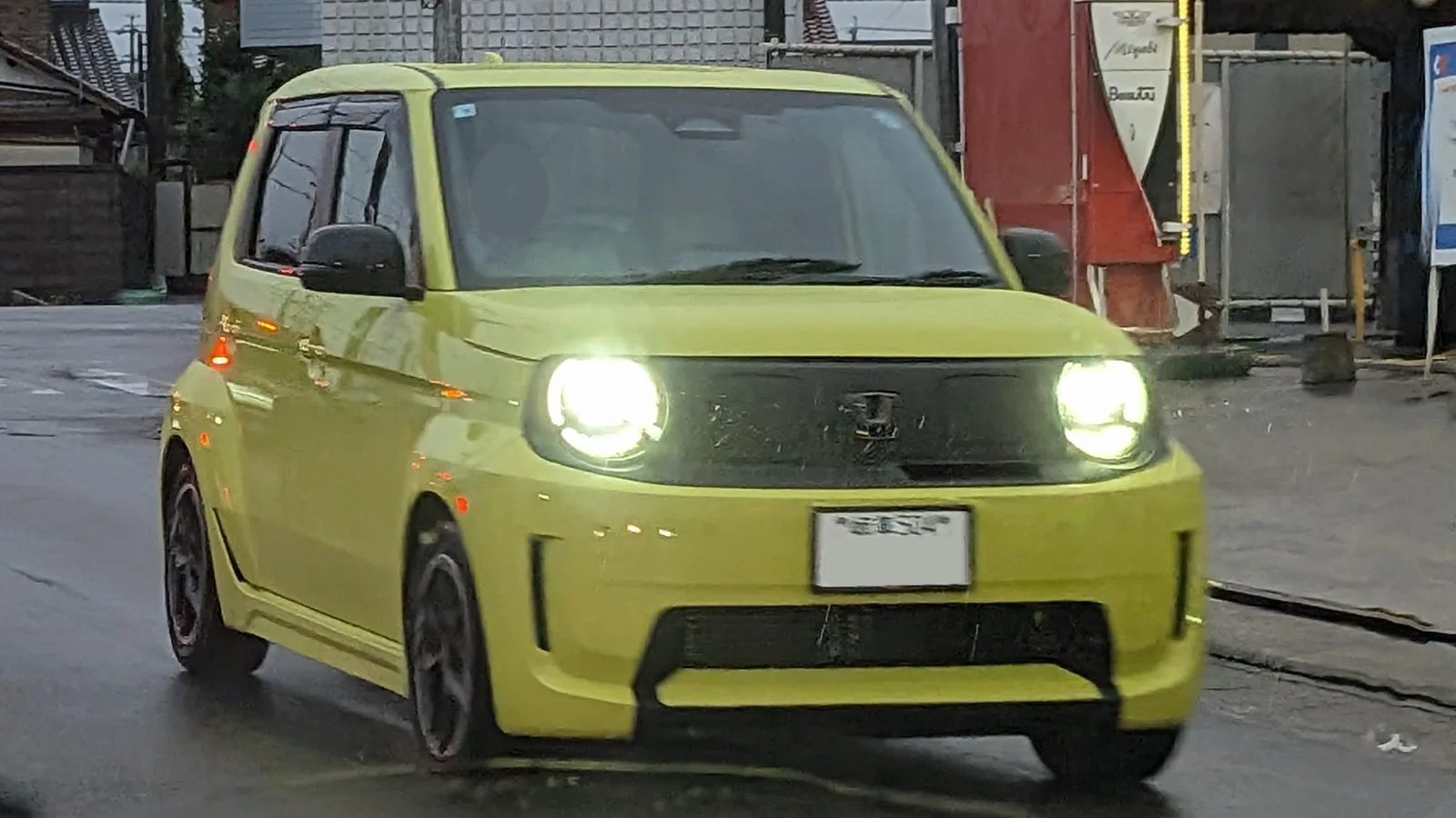 Honda Super-ONE สีเขียวเหลือง เปิดไฟหน้าวิ่งบนถนนญี่ปุ่นยามฝนพรำ