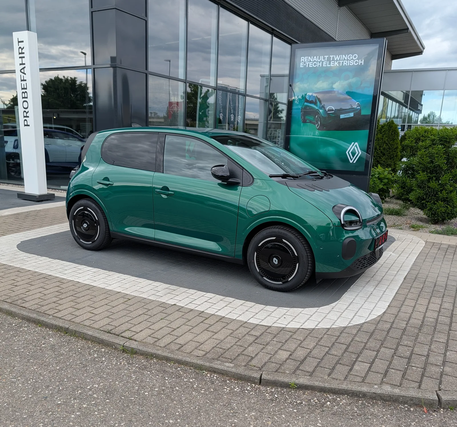 Renault Twingo E-Tech สีเขียว มุมหน้าสามส่วน จอดหน้าโชว์รูม ไฟหน้าวงกลมและล้อดำ