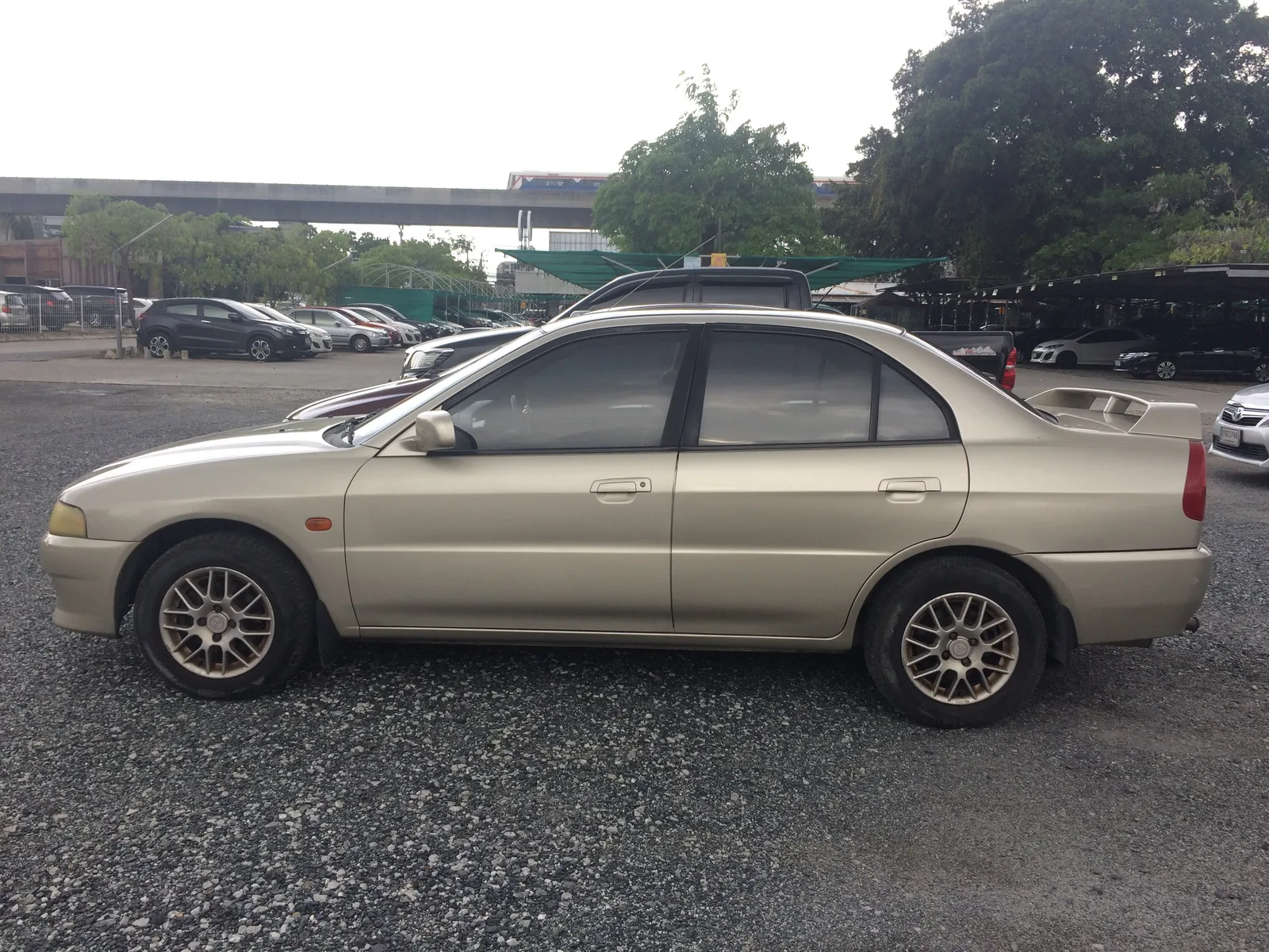 Lancer ท้ายเบนซ์ สีทอง มุมด้านข้างเต็มคัน ล้อแม็กลายตาข่ายและสปอยเลอร์ท้ายแบบสายแต่ง