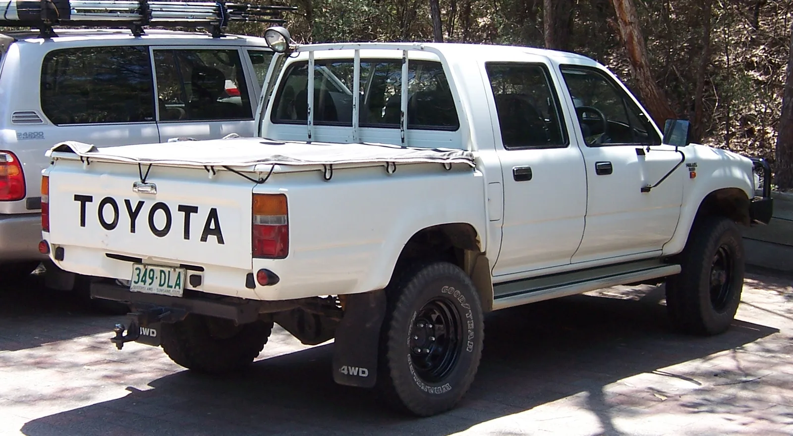Hilux 4WD ตอนคู่สีขาว ฝาท้ายสกรีน TOYOTA ยกสูง ล้อ BF ดำ มุมท้ายสามส่วน