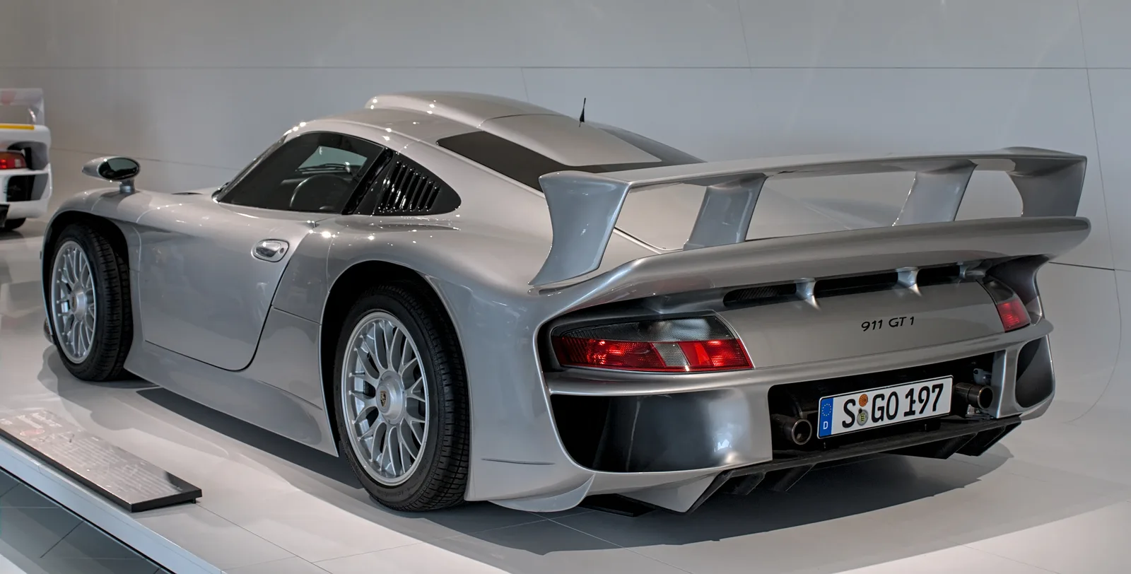 Porsche 911 GT1 Strassenversion สีเงิน มุมท้ายสามส่วน เห็นปีกหลังและไฟท้าย