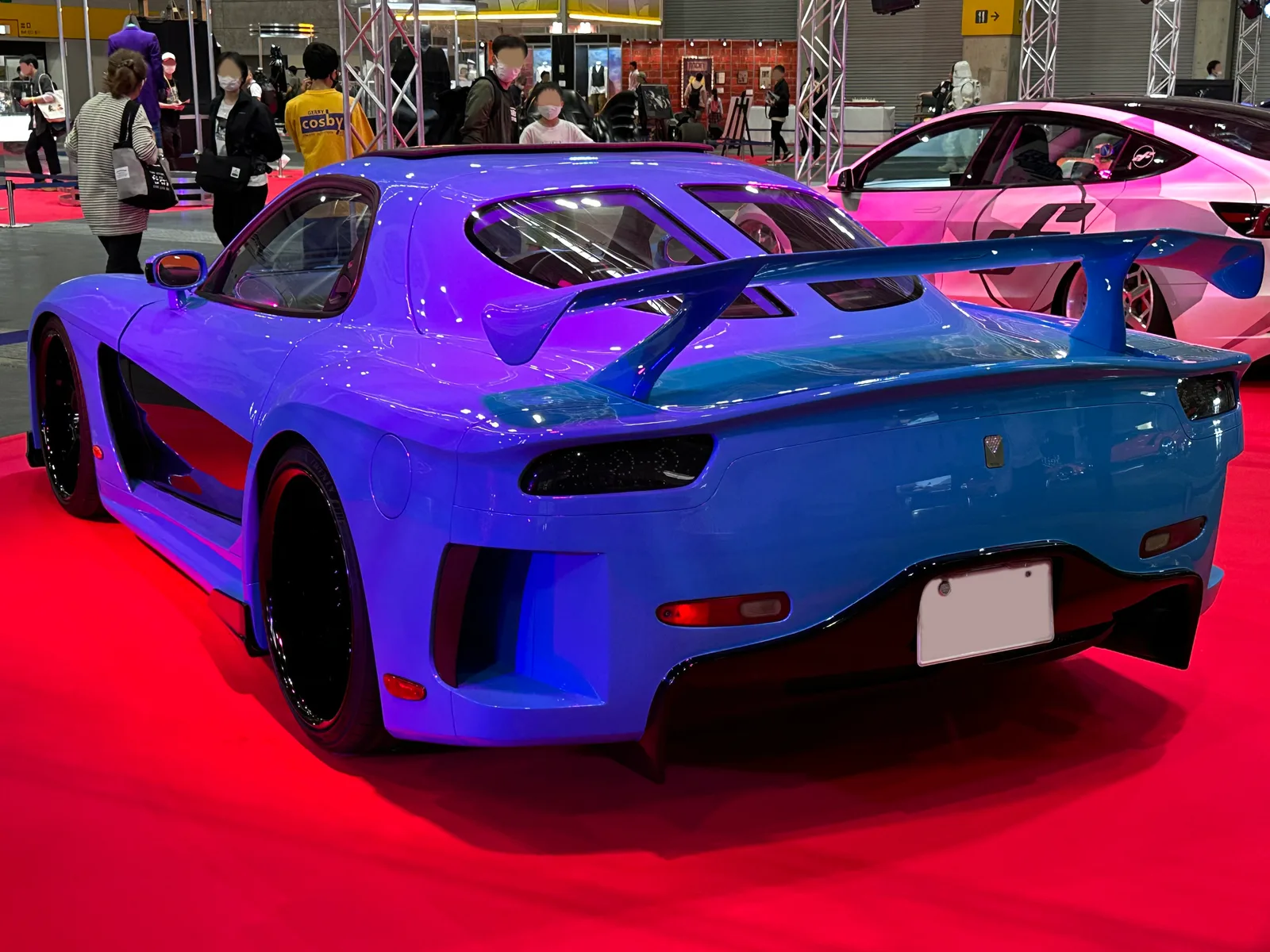 RX-7 Veilside สีน้ำเงิน มุมท้ายสามส่วน เห็นปีกใหญ่และชุดแต่งตัวถังกว้างในงานโชว์ญี่ปุ่น
