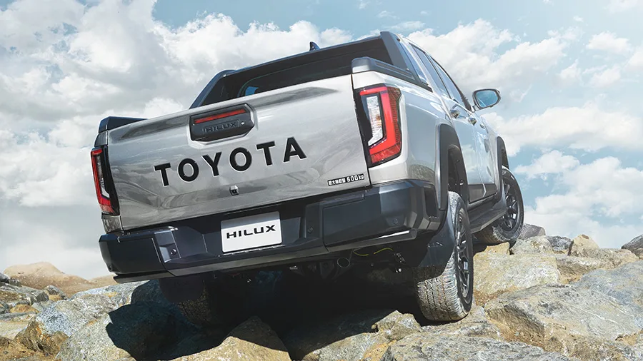 Hilux ใหม่ สีเงิน ท้ายสามส่วน ไฟท้ายแนวตั้งและตัวอักษร TOYOTA บนฝาท้าย บนโขดหิน