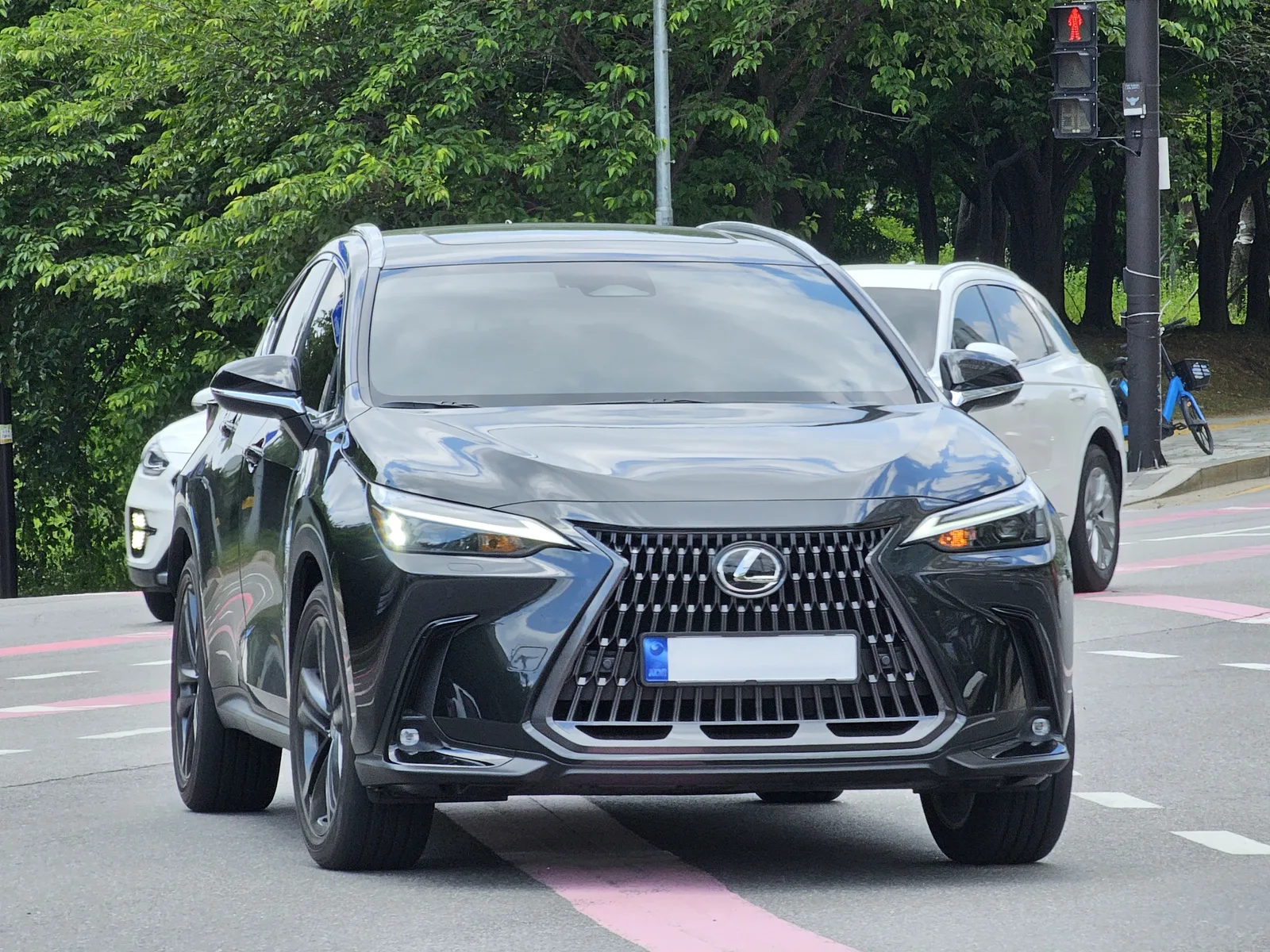 Lexus NX สีดำ มุมหน้าตรงบนถนนจริง เห็นไฟหน้าและกระจังหน้าชัดเจน